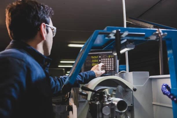 mechanical technician operating a CNC milling machine center at workshop